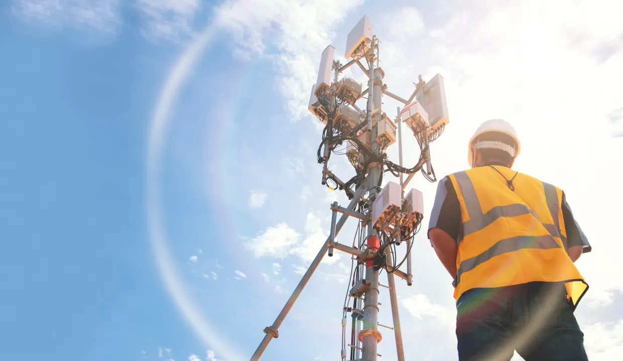 man in front of radio tower servicing infrastructure
